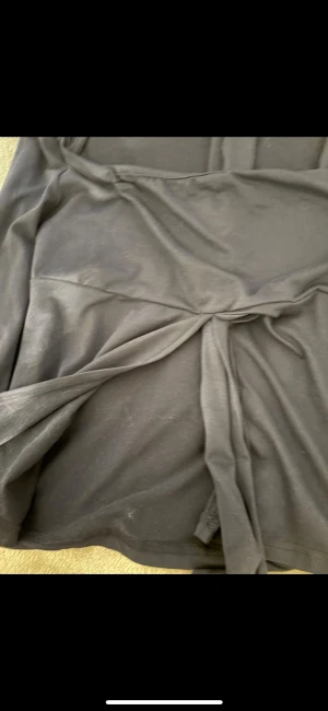 Mörkblå omlottklänning med knyt - Supersnygg mörkblå kortklänning med långa ärmar och omlottdetalj framtill. Klänningen har ett brett knytband över bysten som ger en cool och trendig look. Tillverkad i mjukt och stretchigt material som känns skönt mot huden.