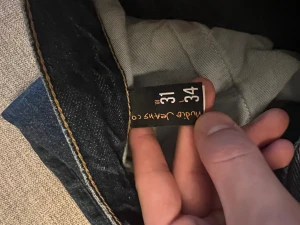 Mörkblå jeans Nudie Gritty Jackson - Snygga mörkblå jeans från Nudie Jeans Co i klassisk femficksmodell med orangea sömmar och ikonisk broderad bakficka. 