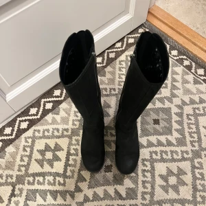 Svarta mockastövlar Timberland Earthkeepers - Snygga svarta stövlar från Timberland, knähöga med rund tå och diskret grovmönstrad sula. Stövlarna har dragkedja på insidan, matt finish i mocka. Funkar både höst och vinter, allround både i stan och i naturen. Passar även mig med strl 38, får plats med varmfodrad sula för den som önskar komplettera. Mycket sparsamt använda. Hög kvalitet. 