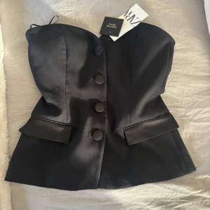 Svart korsettopp från Zara - Snygg svart korsettopp från Zara med knappar framtill och en elegant design💖💖 Toppen har en figurnära passform och är perfekt för en stilren look. Aldrig använd endast provad! Tyvärr slängt lappen😍😍