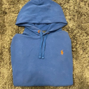 Blå hoodie från Polo Ralph Lauren - Hej, säljer en snygg, blå Ralph Lauren hoodie i storlek L, men som passar bäst på M. Det finns tre små hål, samt några nästan helt osynliga fläckar (se bild). Hör av er vid frågor!