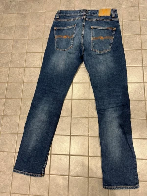 Blå jeans från Nudie Jeans - Säljer ett par Nudie Jeans i modellen Grim Tim som är i storlek W31 L30. Färgen kallas indigo myth. Jeansen är så gott som nya då de var för små för mig.