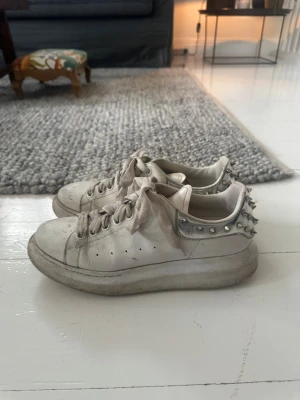 Alexander McQueen sneakers med nitar - Vita sneakers från Alexander McQueen med silvriga nitar på baksidan. Skorna har en hög sula. 