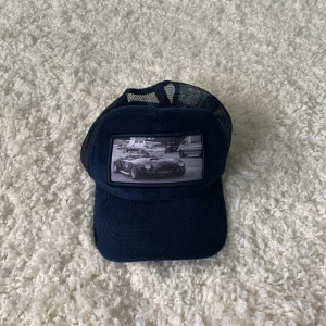 Mörkblå truckerkeps med bilmotiv - Mörkblå truckerkeps med bilmotiv. Använd ca 1 år, i bra skick. Justerbar storlek med snapback och mesh för bra ventilation.