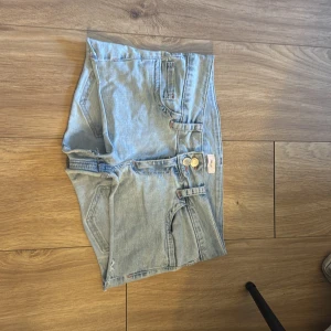 Ljusblå jeansshorts från Nelly - Snygga ljusblå jeansshorts från Nelly med hög midja och råa kanter. Baksidan har coola bakfickor med rödvitt broderat sicksackmönster. Klassisk femficksmodell och dubbla knappar framtill. Perfekta för sommaren!