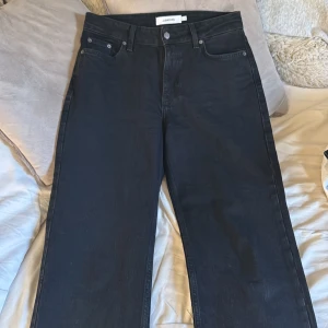 Svarta wide jeans från Junkyard - Säljer ett par svarta jeans från Junkyard med breda ben och klassisk femficksdesign. Jeansen har normal midja och är tillverkade i kraftig denim som ger en snygg och avslappnad look. Perfekta för dig som gillar en trendig och bekväm stil.