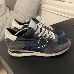 Philippe Model sneakers   - Snygga Philippe Model-trainers i mörkblå och grå färgkombination med vita detaljer. Tillverkade i en mix av mocka, nylon och skinn för en lyxig men sportig look. Väldigt bekväma och lätta på foten.  Väldigt bra skick  Nypris ca 3 000–3 500 kr. Säljes för 1200kr 
