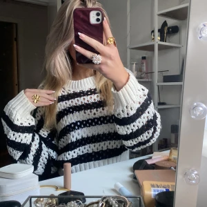 Randig stickad tröja från Gina Tricot - Säljer en stickad tröja från Gina Tricot i storlek M. Tröjan är vit och svart med breda ränder och har ett hålmönster som ger en cool och luftig känsla. Den har rund halsringning, ribbade muddar och långa ärmar. Perfekt för lager-på-lager-stil! Har knappt används💞