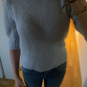 Ljusblå stickad tröja från NA-KD - Superfin ljusblå stickad tröja från NA-KD med puffiga trekvartsärmar och bred ribbad mudd vid hals, ärmslut och nederkant. Perfekt för dig som gillar en enkel men ändå trendig look. Snygg att styla med jeans eller kjol. Längd 50 cm bred 39 cm