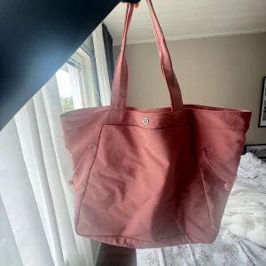 Lululemon - Stor och rymlig rosa gymväska från Lululemon med dubbla handtag och praktiska dragskor på sidorna. 