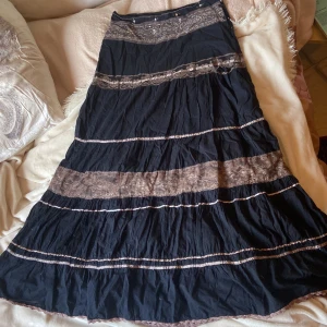 Långkjol  - Svart långkjol med fina detaljer och påsydda knappar (dragkedjan funkar inte längre). Ända defekten är att tyget är lite sprucket längst ner på dragkedjan. Skriv gärna om ni vill ha fler bilder eller har frågor 