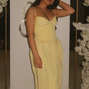 Oh Polly Ljusgul långklänning med smala axelband - Supersnygg ljusgul långklänning med smala axelband och figurnära passform. Klänningen har en djup urringning och vågiga detaljer längs kjolen som ger en unik look. Perfekt för dig som vill sticka ut med en feminin och elegant stil. Klänningen är i storlek 6/XS och är använd endast en gång så den är i mycket bra skick💛