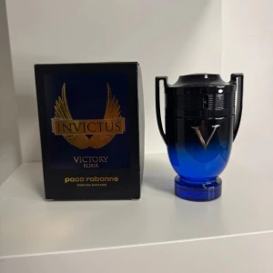Paco Rabanne Invictus Victory Elixir - Parfymen Invictus Victory Elixir från Paco Rabanne kommer i en cool blå och svart troféformad flaska med silverdetaljer. Doften är intensiv och exklusiv, perfekt för dig som vill sticka ut. Förpackningen är svart med guldiga vingar och text.