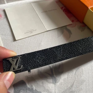 Skinn armbands bälte - Säljer ett svart bälte i exklusivt präglat skinn med ikoniskt i silver. Bältet har en stilren och klassisk design, perfekt för att lyfta vilken outfit som helst. Levereras med originalbox, dustbag och äkthetskort.