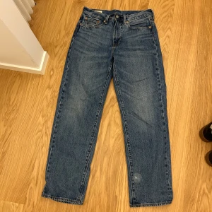 Levi's 505 W31 L32 - Säljer ett par klassiska Levi's Stay Loose jeans i blå denim. Modellen har en loose passform med raka ben. Det är en liten sliten detalj på ena benet, vet inte hur den har tillkommit men man ser inte det när man använder de. Perfekta för en avslappnad streetstil.