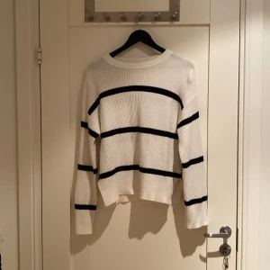 Vit och svart randig stickad tröja Kappahl - Säljer en vit stickad tröja från Kappahl med svarta horisontella ränder. Tröjan har rund halsringning, lång ärm och en lite boxig passform. Har använt några gånger.