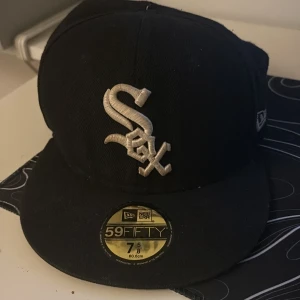 Svart New Era 59FIFTY White Sox keps - Säljer en svart New Era 59FIFTY keps med broderad White Sox-logga framtill och World Series-märke på sidan. Klassisk flat peak och äkta MLB-merchandise. Har använt i ett år, behöver inte längre 