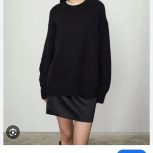 Lisa Yang Tröja - En svart, oversized stickad tröja med rund halsringning och långa ärmar. Tröjan har en enkel och clean look med breda muddar vid ärmslut och nederkant. Perfekt för lager-på-lager och chill stil.