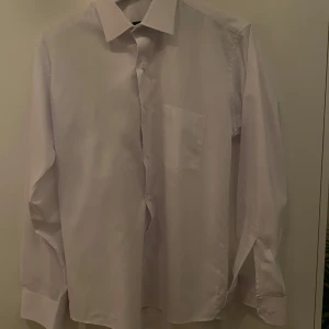 Vit skjorta från Massimo Dutti - Klassisk vit skjorta från Massimo Dutti med lång ärm, bröstficka och knappar framtill. Skjortan har en stilren krage och är tillverkad i bomull, perfekt för en clean och snygg look.