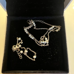 Silverhalsband och armband med pärlor - Säljer ett tunt silverhalsband och matchande armband med små vita pärlor. Köpt i Danmark, minns tyvärr inte vad märket heter. Äkta silver.