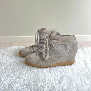 Intressekoll på mina Isabel marant liknande skor - Snygga beige sneakers med kilklack och snörning. Skorna är gjorda i mocka med perforerade detaljer och har en gummisula. Står att det är storlek 41 men skulle mer säga 39! Passar perfekt och jag brukar ha 38 i skor!