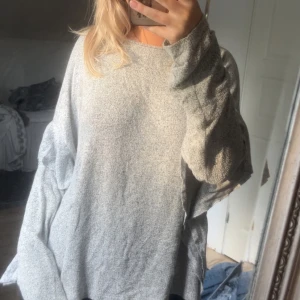 Grå oversized stickad tröja H&M - Supermjuk och oversized grå stickad tröja från H&M. Tröjan har en lös passform, rund halsringning och långa ärmar. Perfekt för lager-på-lager och chill dagar. Enkel att matcha med jeans eller leggings.