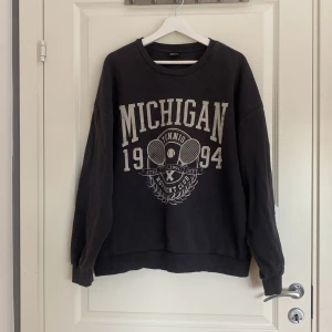 Svart oversized Michigan sweatshirt XL - Cool svart sweatshirt från Gina Tricot i oversized modell med tryck 'Michigan 1994 Tennis Movement Club' framtill. Mjuk insida och långa ärmar, perfekt för en avslappnad look. Passar dig som gillar sportiga och bekväma plagg.