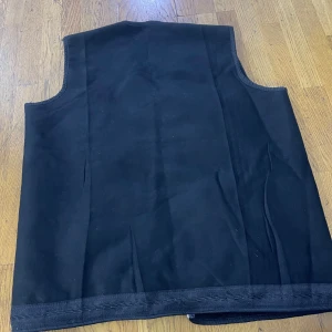 Svart fodrad väst med dragkedja - Svart väst med rak passform, två stora fickor framtill och dragkedja. Västen har ett mjukt, fodrat innerfoder och breda kantband längs öppningen. Perfekt för lager-på-lager och enkel att matcha med olika outfits.