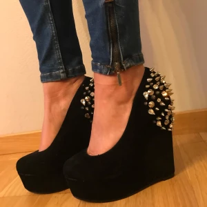 Kilklackar - Kilklackar från Nelly med hög platå och klack. Baksidan är täckt av silvriga nitar och strass, några har lossnat på ena skon (Se bild) men det är inget man lägger märke till men det medföljer diamanter som jag fick med när jag köpte dom. Storlek 37