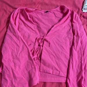 Rosa omlottopp med knytband - Säljer en snygg rosa omlottopp med långa ärmar. Har bara använts ett par gånger. Pris kan diskuteras.