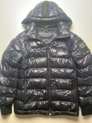 Peak Performance dunjacka - Säljer en mycket fin marinblå dunjacka från Peak Performance. Jackan är både praktisk och snygg. Den har dragkedja, fickor, huva och logotyp på vänstra ärmen. Går att styla till allt, är väldigt behaglig och håller en varm. Jackan är värderad till ett nypris på 2100 kr. Säljer på grund av att den inte passar mig. Priset är inte hugget i sten!