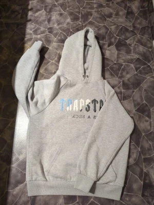 Grå trapstar hoodie -   Säljer min gråa Trapstar hoodie!  Storlek M och nästan som ny – har knappt använt den. Den är superbekväm och perfekt för alla tillfällen!