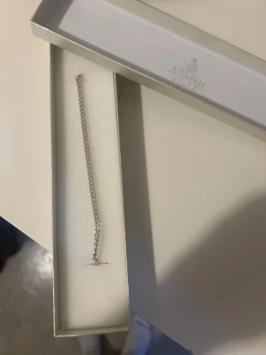 Silverfärgad pansarlänk armlänk 18 cm - Snygg armlänk från Albrekts Guld i äkta silver med klassisk pansarlänk-design. Länken är 18 cm lång och har ett stilrent, silverfärgat utseende med smidig karbinlås. Perfekt för dig som gillar enkla och tidlösa smycken.