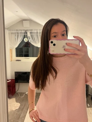 Ljusrosa stickad topp från Gina Tricot - Superfin ljusrosa stickad topp från Gina Tricot i storlek XS. Modellen har korta ärmar, rund halsringning och mjukt material som känns skönt mot huden. Perfekt att styla med jeans eller kjol för en söt och enkel look.