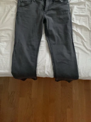 Mörkgrå jeansbyxor Style Sharp 31/32 - Snygga mörkgrå jeansbyxor från Progr. Moving i modellen Style Sharp. Klassisk femficksdesign och raka ben. Perfekta för dig som gillar en enkel och stilren look. Storlek 31/32.