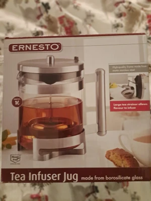 ERNESTO Tea Infuser Jug / Tepress – Oanvänd i originalförpackning - Ernesto Tea Infuser Jug / Tepress – Oanvänd i originalförpackning Säljer en Ernesto Tea Infuser Jug (tepress/teinfuser-kanna) i helt nyskick. Aldrig använd – endast förvarad i originalförpackning. ERNESTO tekanna tillverkad av borosilikatglas. Högkvalitativ ställning av matt specialstål. Stor tesil som låter aromen utvecklas på ett optimalt sätt. Oanvänd, Originalförpackning, Instruktionsbok medföljer, värmebeständig upp till 100 °C ,kannan lätt att rengöra & tål maskindisk& locket ej maskindisk