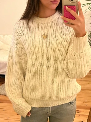 Cremevit Bige Vit stickad tröja från Pull&Bear - Säljer en vit stickad tröja från Pull&Bear i storlek S. Tröjan har en grovstickad struktur, rund hals och ribbade muddar vid ärmslut och nederkant. Passformen är loose och den är långärmad, perfekt för kyliga dagar.