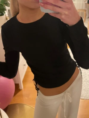 Svart långärmad topp med snörning - Säljer en svart långärmad topp med snörning i sidorna. Jättesnygg! Jättebra skick! Knappt använd! Storlek xs