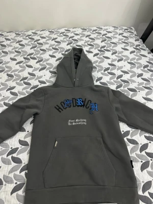 Hoodrich tröja  - Det är en väldigt unik tröja som är grå med flera fickor det finns ganska mycket detaljer på båda hållen 