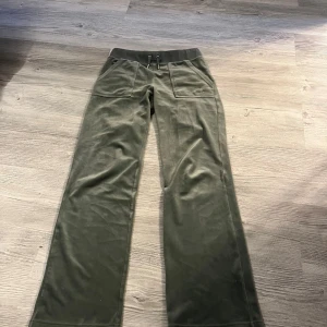 Olivgröna mjukisbyxor med snörning - Olivgröna mjukisbyxor i mjuk sammet med bred resår och snörning i midjan. Byxorna har raka ben, stora fickor fram och bakfickor med knapp. Perfekta för en chill och avslappnad stil.