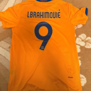 FC Barcelona Ibrahimović Nike tröja - Säljer en FC Barcelona fotbollströja med Ibrahimović och nummer 9 på ryggen. Tröjan är orange med blå detaljer, har klubbmärke och Unicef-tryck på bröstet. Tillverkad i lätt och ventilerande NikeFIT-material, perfekt för match eller träning.