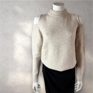 Mango stickad  tröja - Snygg beige stickad tröja från Mango med offshoulder-detalj och hög hals. Tröjan har långärmade ärmar och är tillverkad i ett mjukt, fluffigt material som ger en cozy vibe. Perfekt för dig som gillar trendiga detaljer och vill ha något som sticker ut. #wollbland #mango #tröja