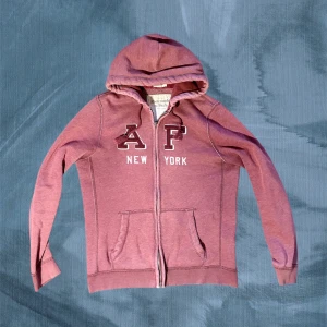 Vinröd hoodie från Abercrombie & Fitch - Tvärrrsnygg hoodie från Abercrombie & Fitch i stl L Väldigt trendig och sällsynt med bara några få fel vilket ger den en vintage look. Sjukt eftertraktad och limiterad colorway samt modell . Lämna gärna ett prisförslag så kommer vi överens om nåt! Ha det tiptop// Gidlöfs