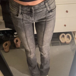 Grå jeans med markerade sömmar - Snygga grå jeans från Bershka med markerade sömmar längs benen och klassisk femficksdesign. Modellen har låg midja och bootcut med en lätt tvättad look. Perfekt för dig som gillar en cool och modern stil.
