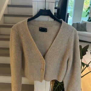 Beige ribbad kofta från ASOS Design - Supermysig beige kofta från ASOS Design med ribbstickat material och två stora knappar framtill. 