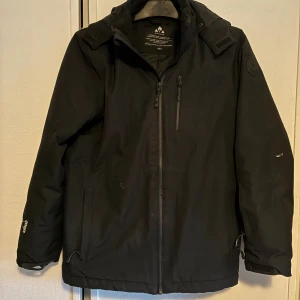 Svart vinterjacka från Whistler strl 164/14years - Svart vinterjacka från Whistler med huva, dragkedja framtill och flera praktiska fickor. Jackan har en stilren look och är tillverkad i slitstark polyester. Perfekt för dig som gillar funktionell och enkel stil. Passar dig som vill ha en jacka med clean vibe. Färgfläckar finns, se bilder. Försvinner ev vid tvätt. 