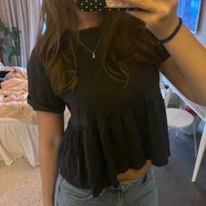 Svart peplumtop från Bershka - Svart topp från Bershka med volang nedtill och korta ärmar. Jättesöt!! Används tyvärr inge längre 🩷🩷🩷