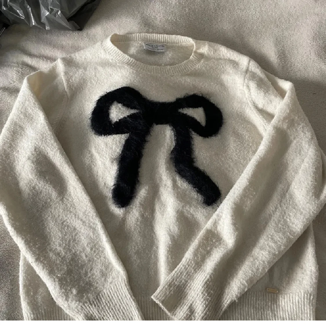 Vit stickad tröja med svart rosett