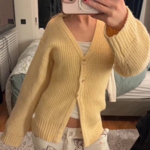 Gul ribbad kofta med v-ringning - Supermysig gul kofta med v-ringning och stora knappar framtill. Den är ribbstickad och har långa ärmar med en lite loose passform. Perfekt att slänga på sig när det är kyligt ute.