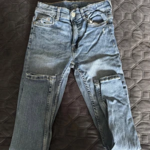 Blå jeans med cargofickor från Zara - Säljer ett par blå superelastiska jeans från Zara med coola cargofickor på benen. Jeansen har klassisk femficksdesign, dragkedja och knapp framtill. Perfekta för dig som gillar streetstyle och vill ha något bekvämt och snyggt.